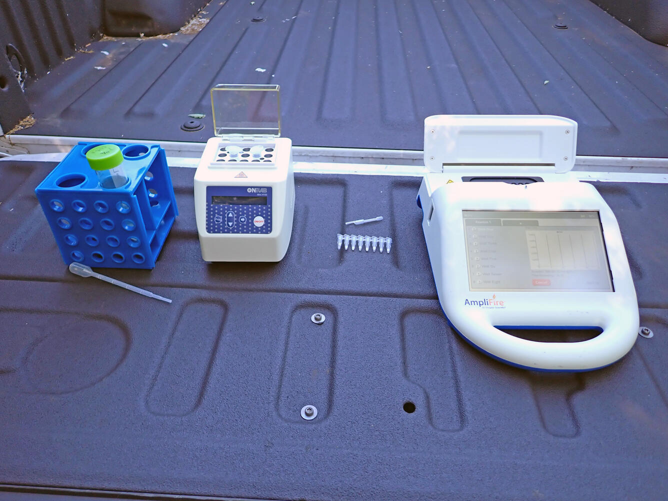 several pieces of a portable DNA rapid test kit placed on the lowered tailgate of a pickup truck