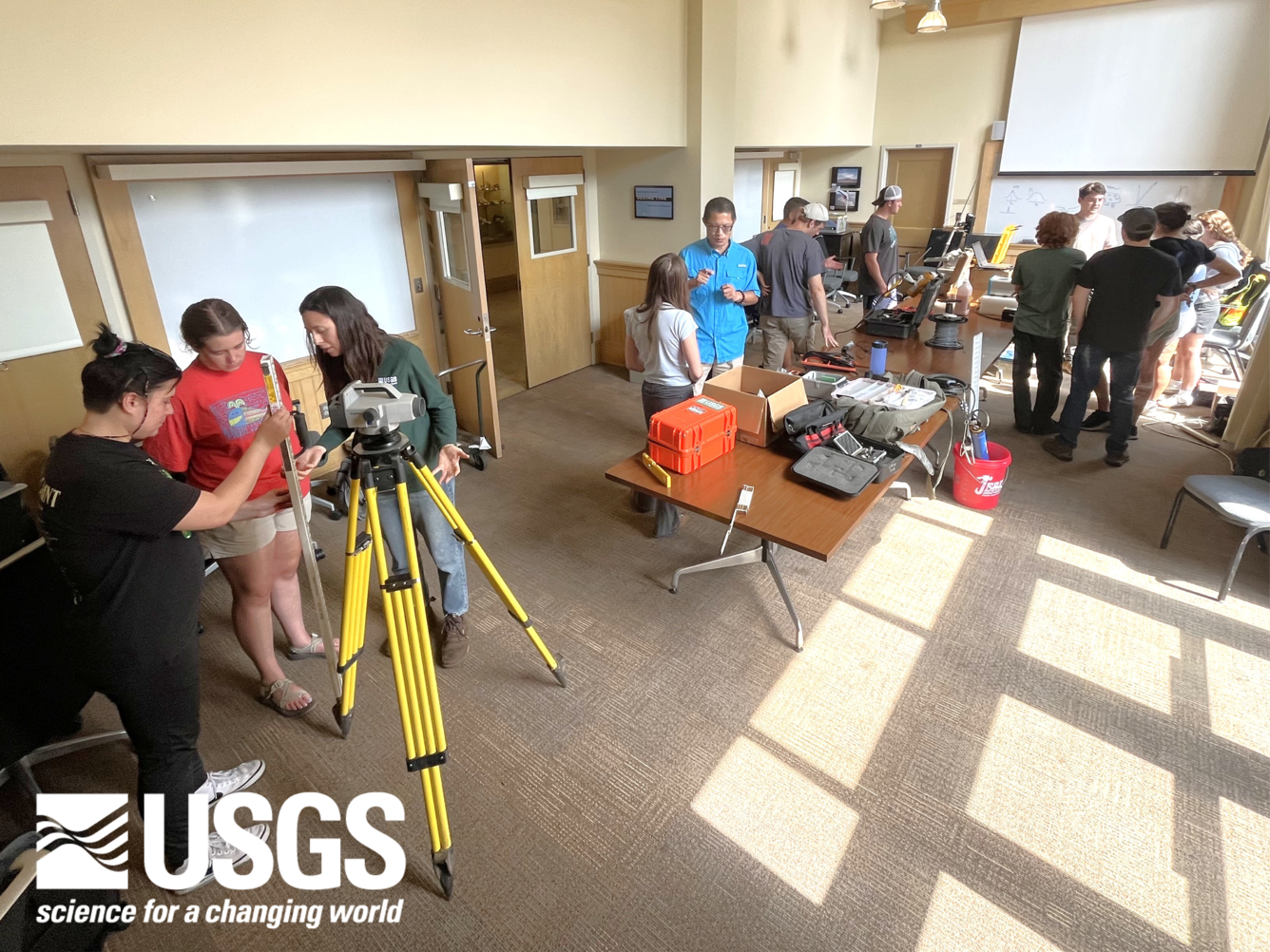 groups of students in a well-lit room huddle around various stations of equipment demonstrations