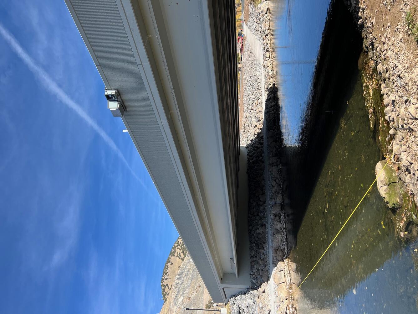Looking up from stream to gage shelter on side of bridge.