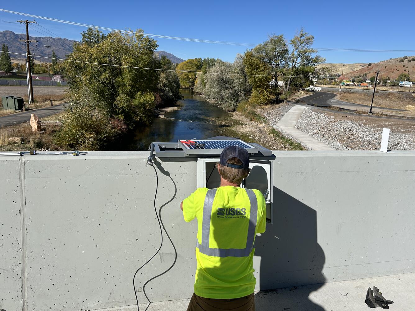 Employee kneels on bridge with view of river in front from bridge.