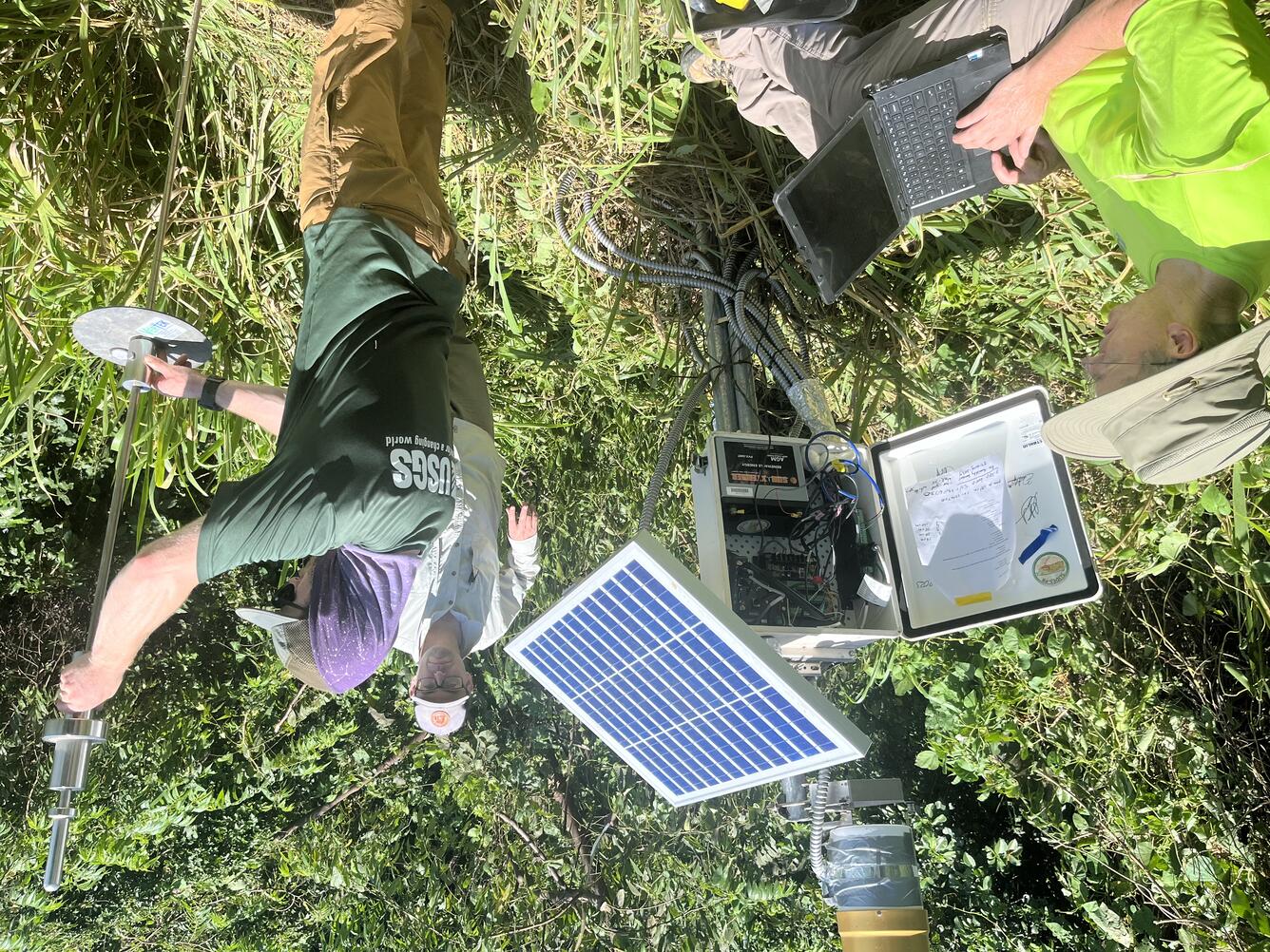 Three scientists next to completed landslide monitoring station