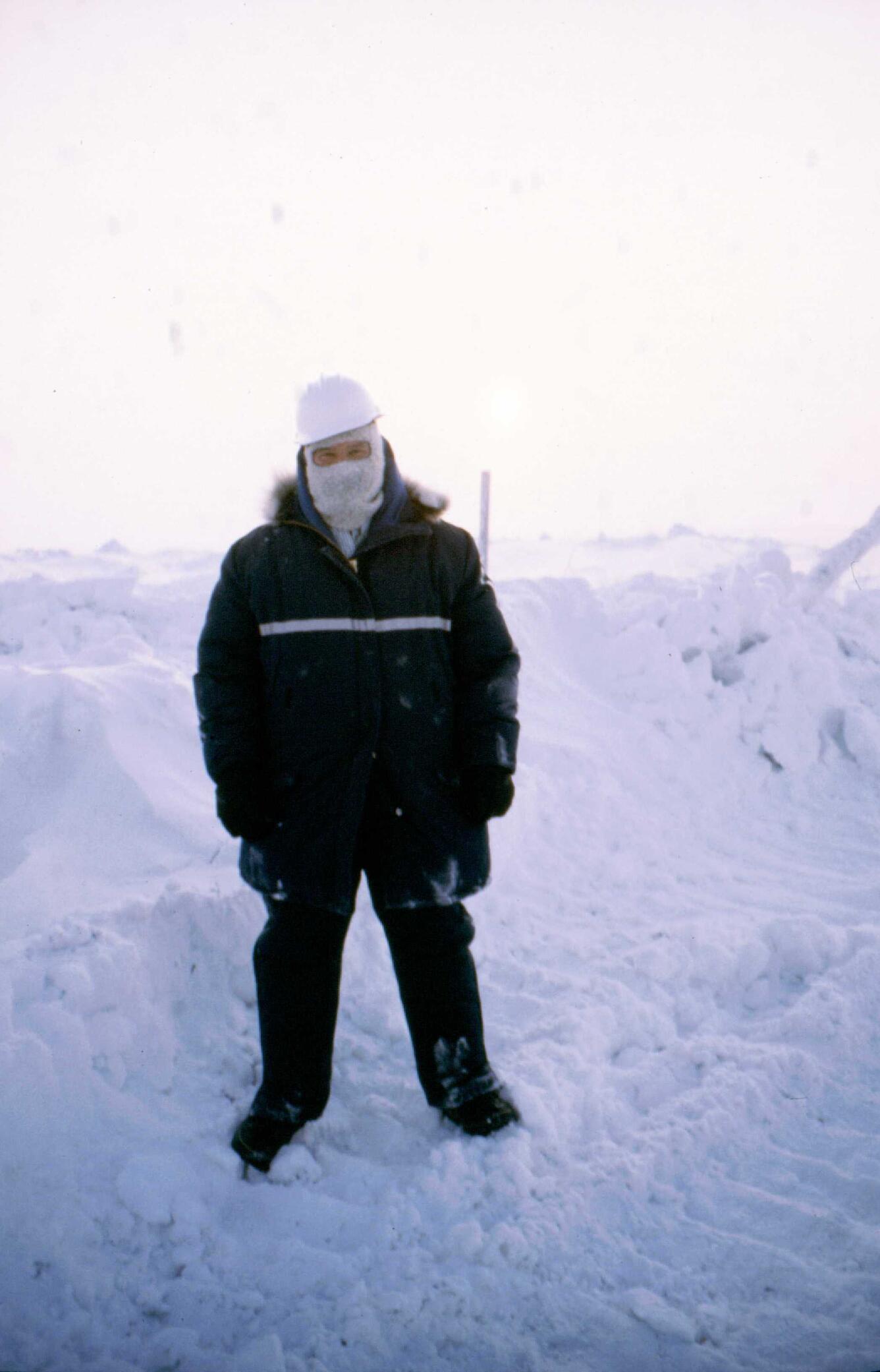 Man standing in front of a snowy backdrop wearing heavy winter gear.