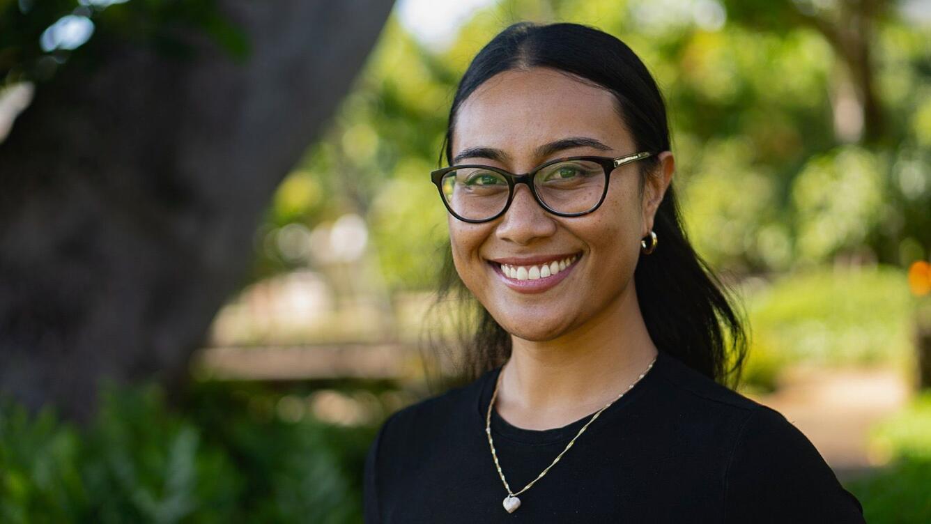 A woman with dark hair and glasses smiles for her picture. 