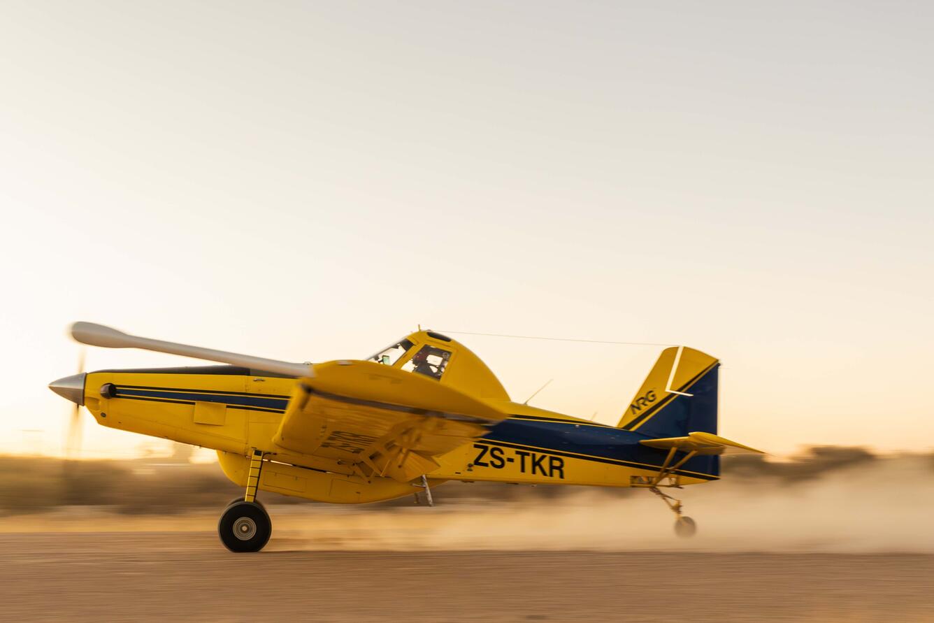 A yellow and dark blue single-engine agricultural aircraft (registration ZS-TKR)