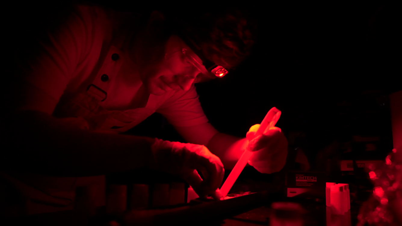 Physical scientist Zach Clifton studies sediment samples in a dark room with red light.
