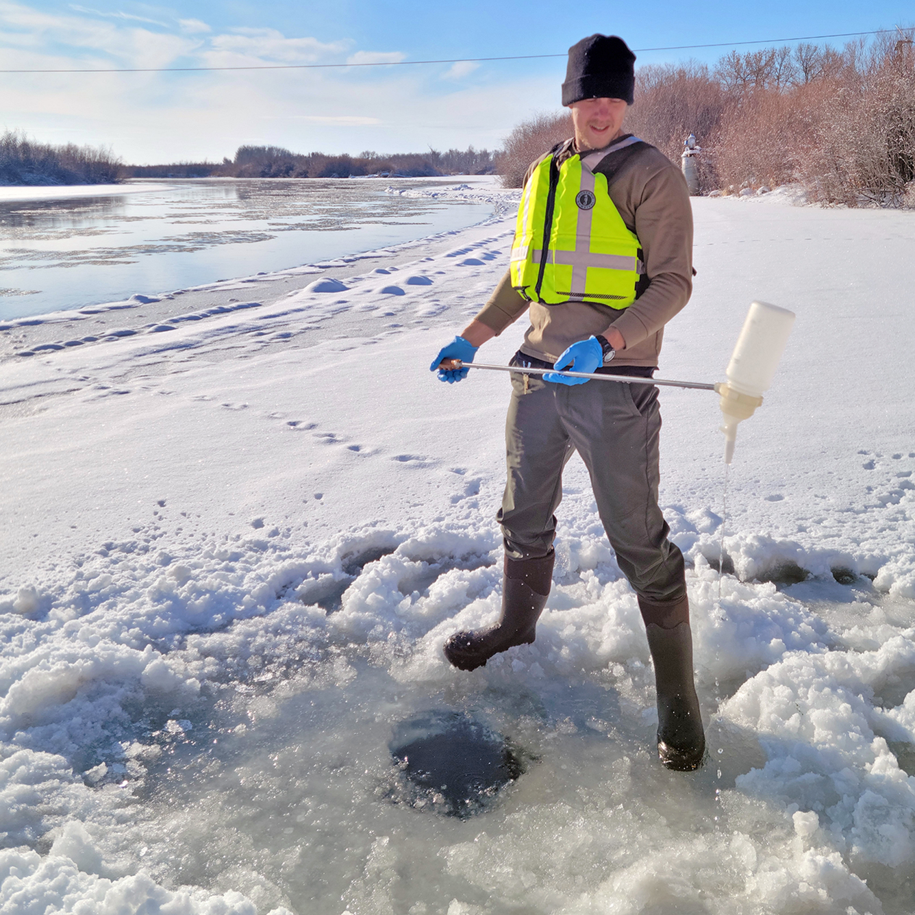 U.S. Geological Survey hydrologist Jeff Zingre retrieves a water sample from a hole through the ice over an Idaho river.