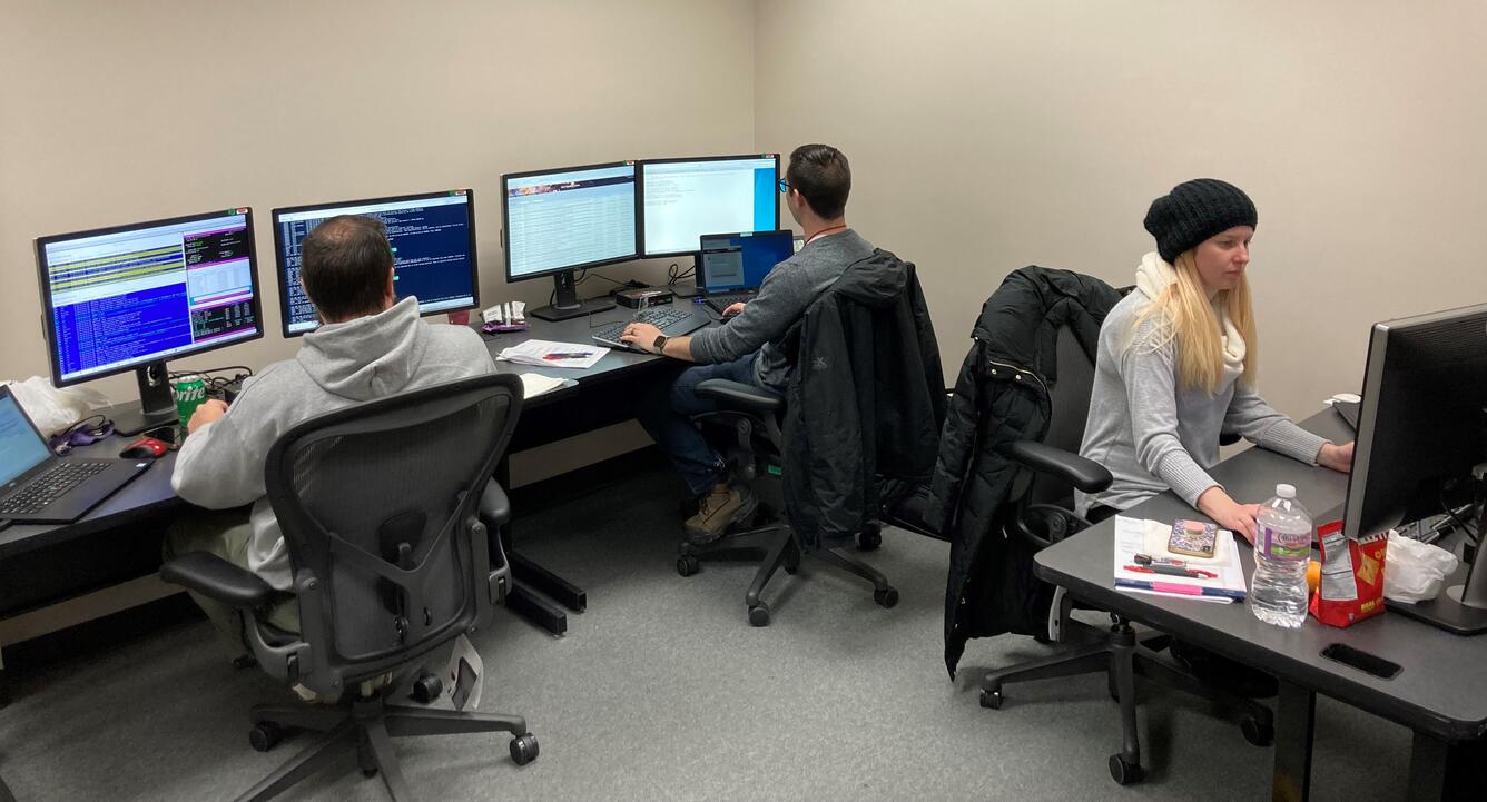 Two men and a woman work on computers