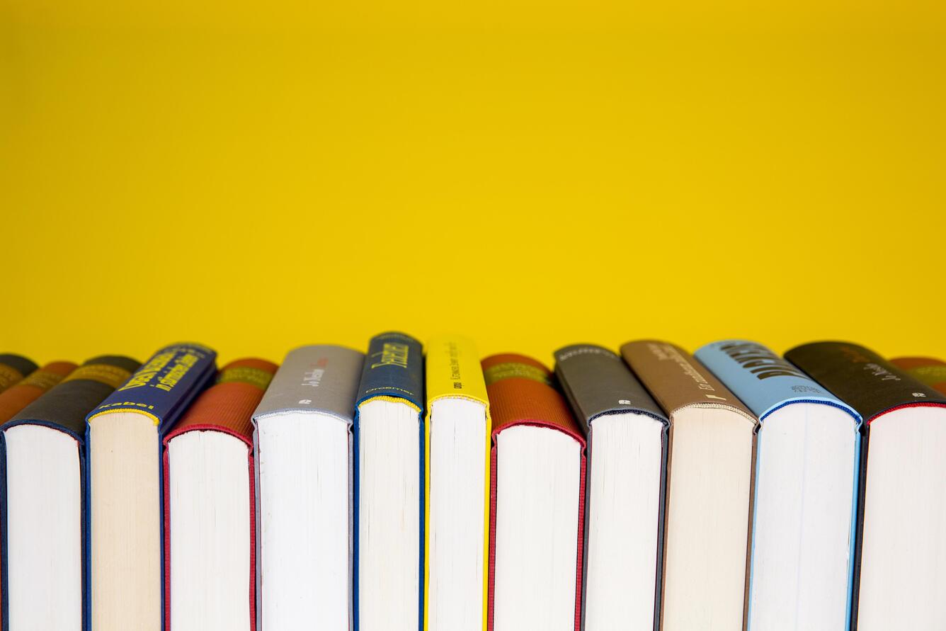 Books lined up with spines facing upward against a yellow background