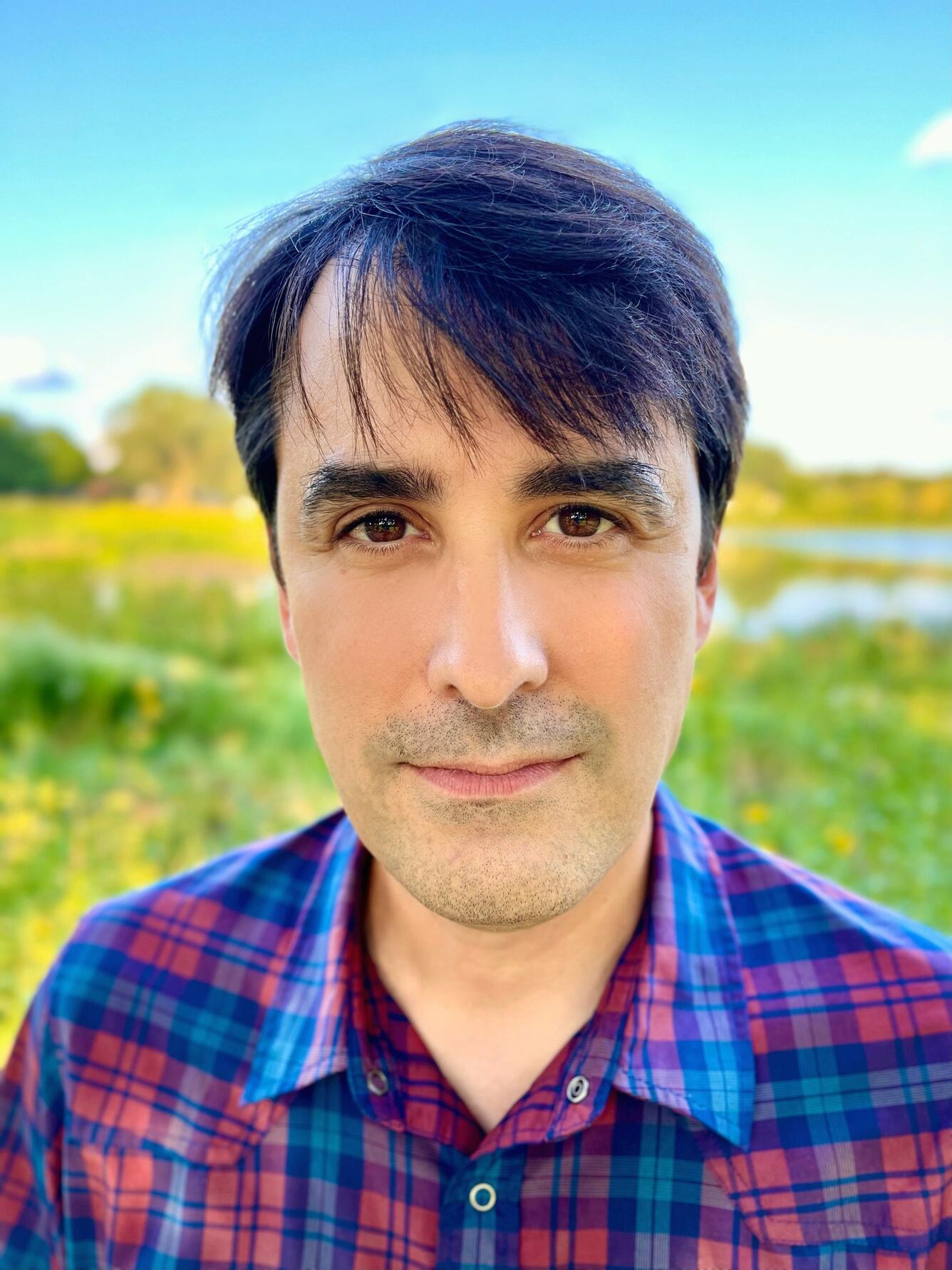 male scientist with brown hair, brown eyes wears a checkered red and black shirt