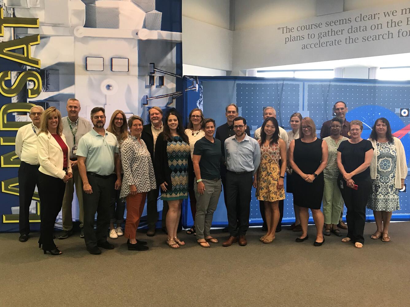 Photo of the USGS Core Science Systems, Senior Leadership Team group standing in front of LANDSAT mural.