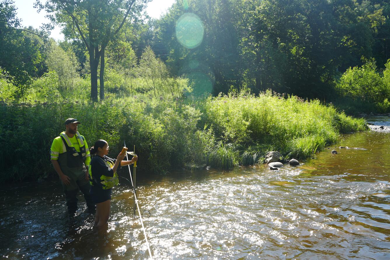Two people standing in a stream take a discharge measurement
