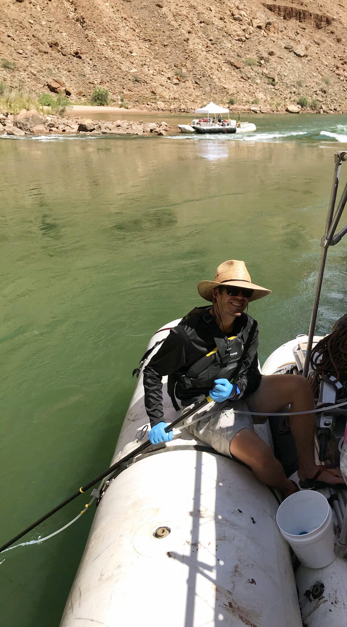 On a research boat in the Grand Canyon, a man collects samples from the Colorado River using an eDNA sampler.