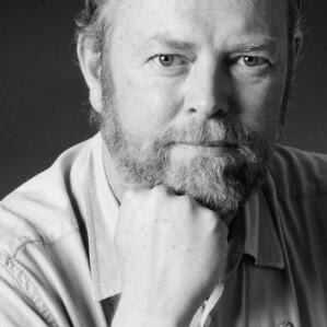 A black and white image of a man resting his chin in his hand.