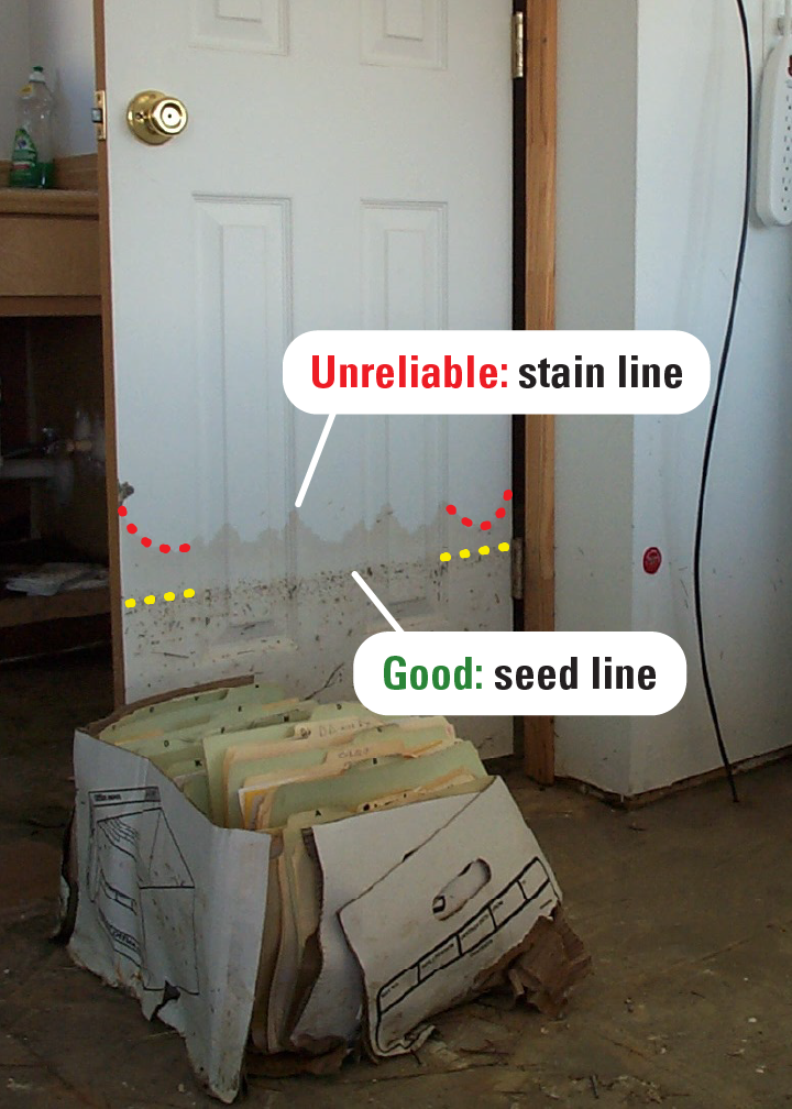 A stain line on a wood door that has absorbed floodwater. 