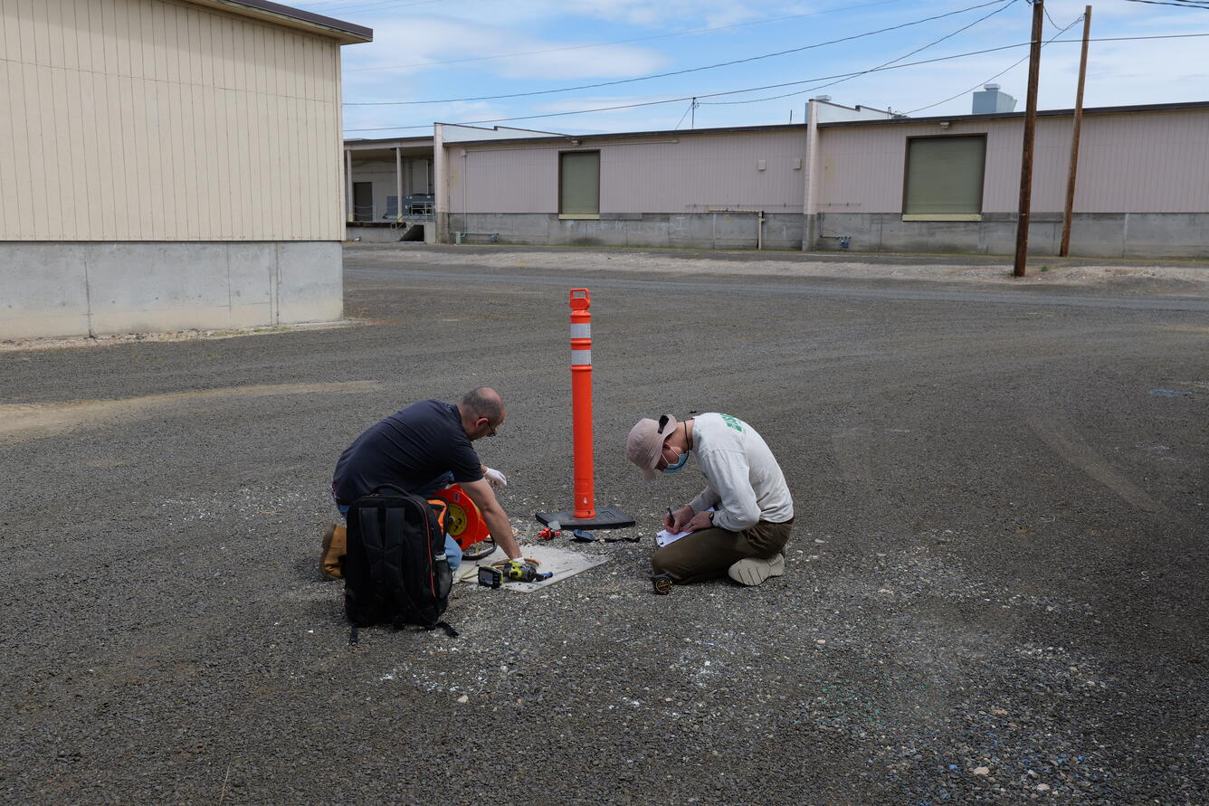 Scientists measure well in a gravel lot