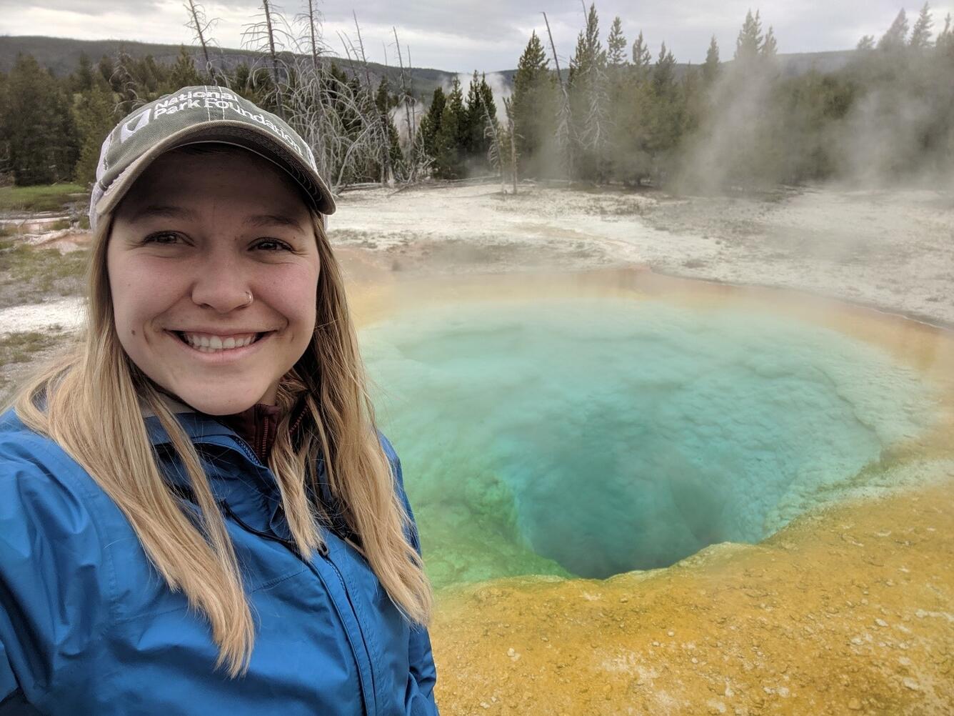 Photograph of USGS physical scientist Holly Buban in front of a hot spring.
