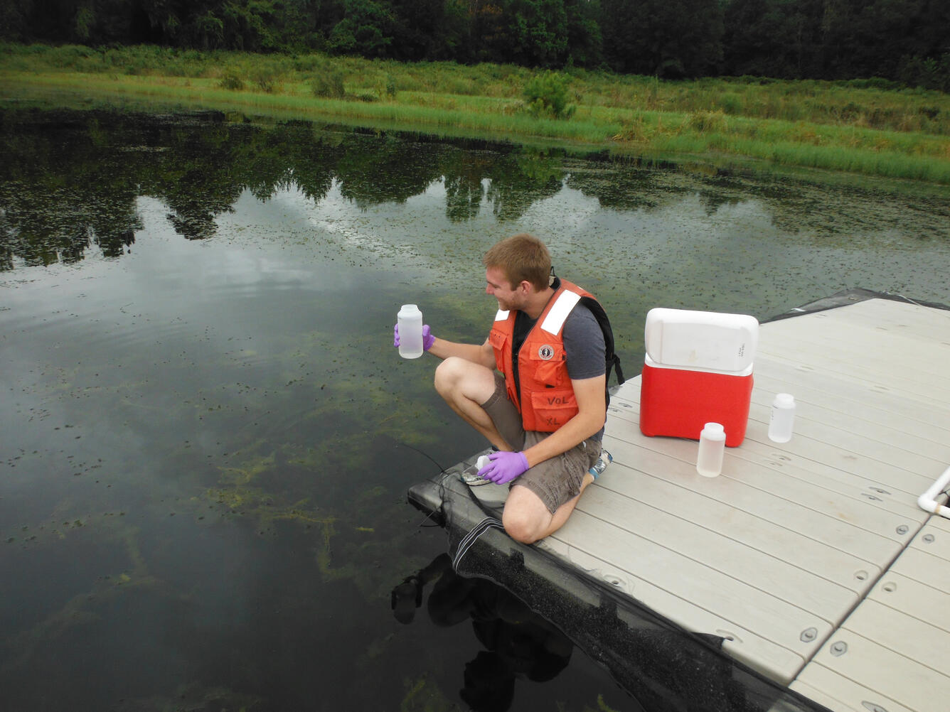 Man sitting on a dock holds a filled water bottle