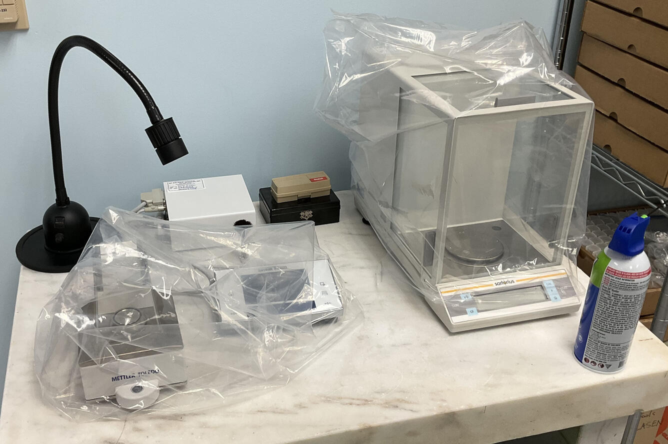 three high-precision micro-balances covered with plastic sit on laboratory table