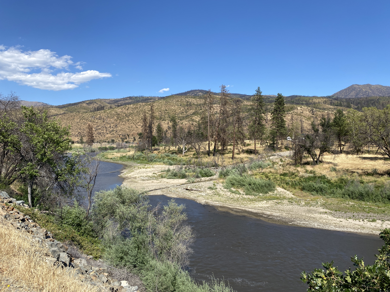 Dry mountain with a few trees near a river