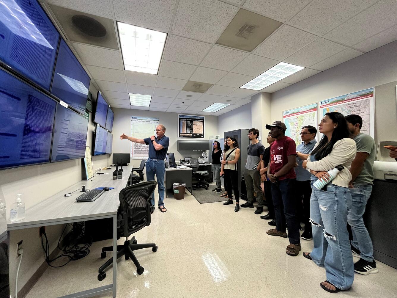 Inside the Operations Room at the Cascades Volcano Observatory. Scientists look at large monitors displaying data. 