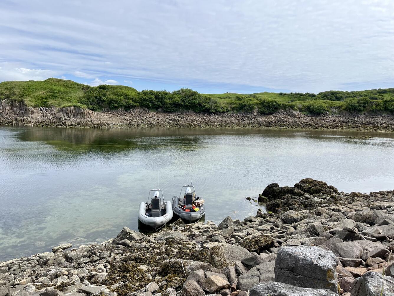 Two boats anchored to a rocky shoreline.