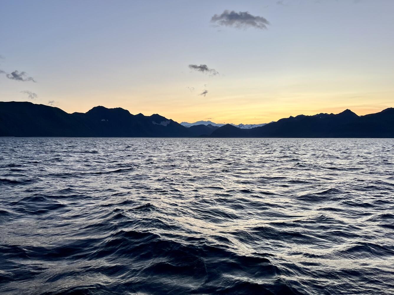 Yellow sunset over mountains and water.
