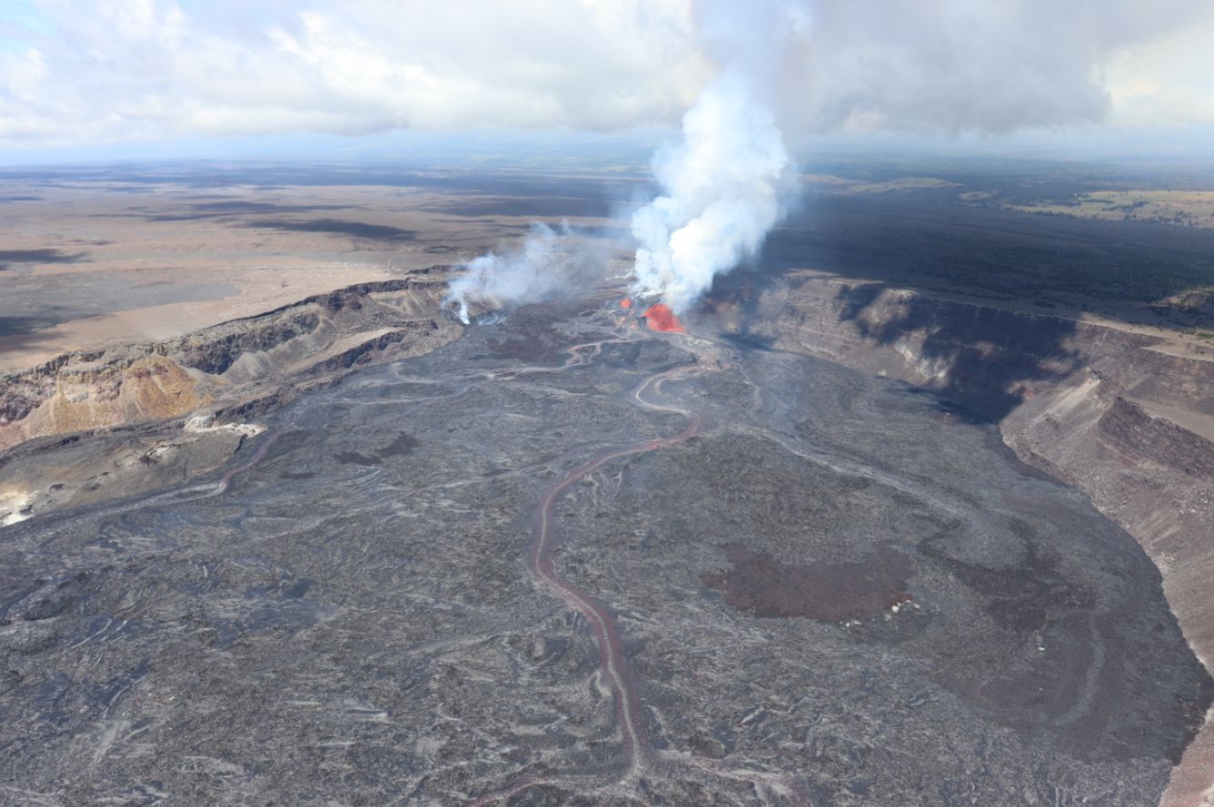 Aerial view of a lava fountain erupting in a crater and feeding several streams of lava across the crater floor