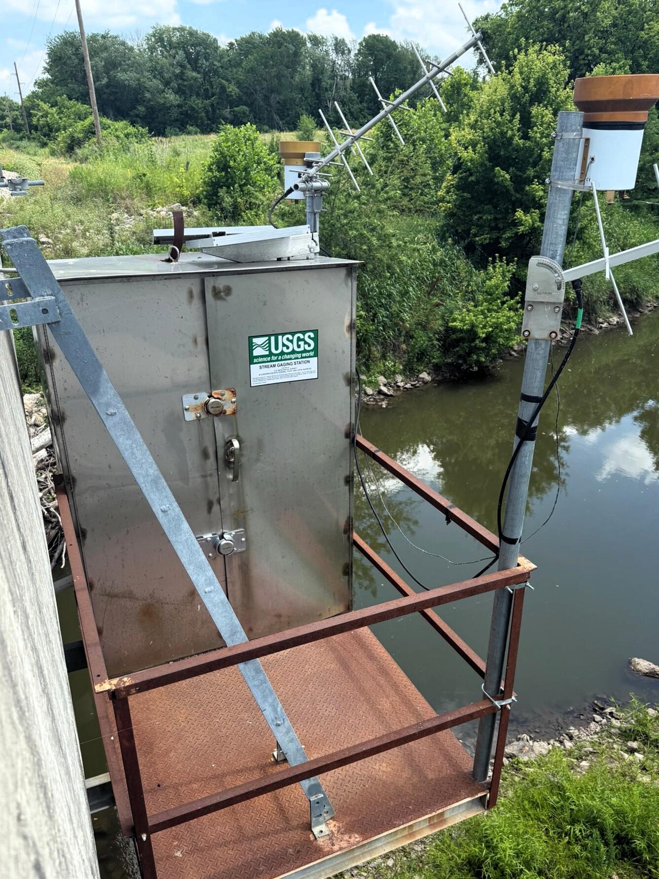 Streamgage housing on bridge on a summer day
