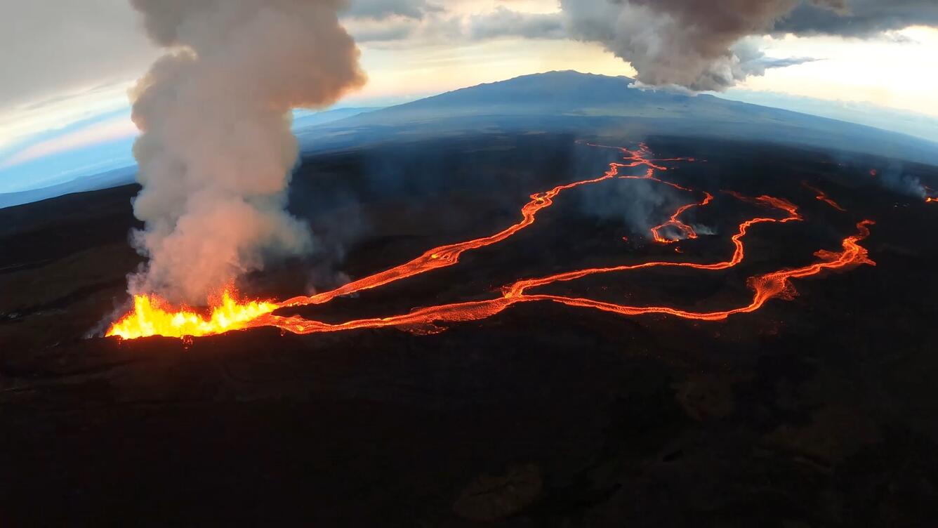 Lava erupting with lava flows streaming down a mountain looking from overhead