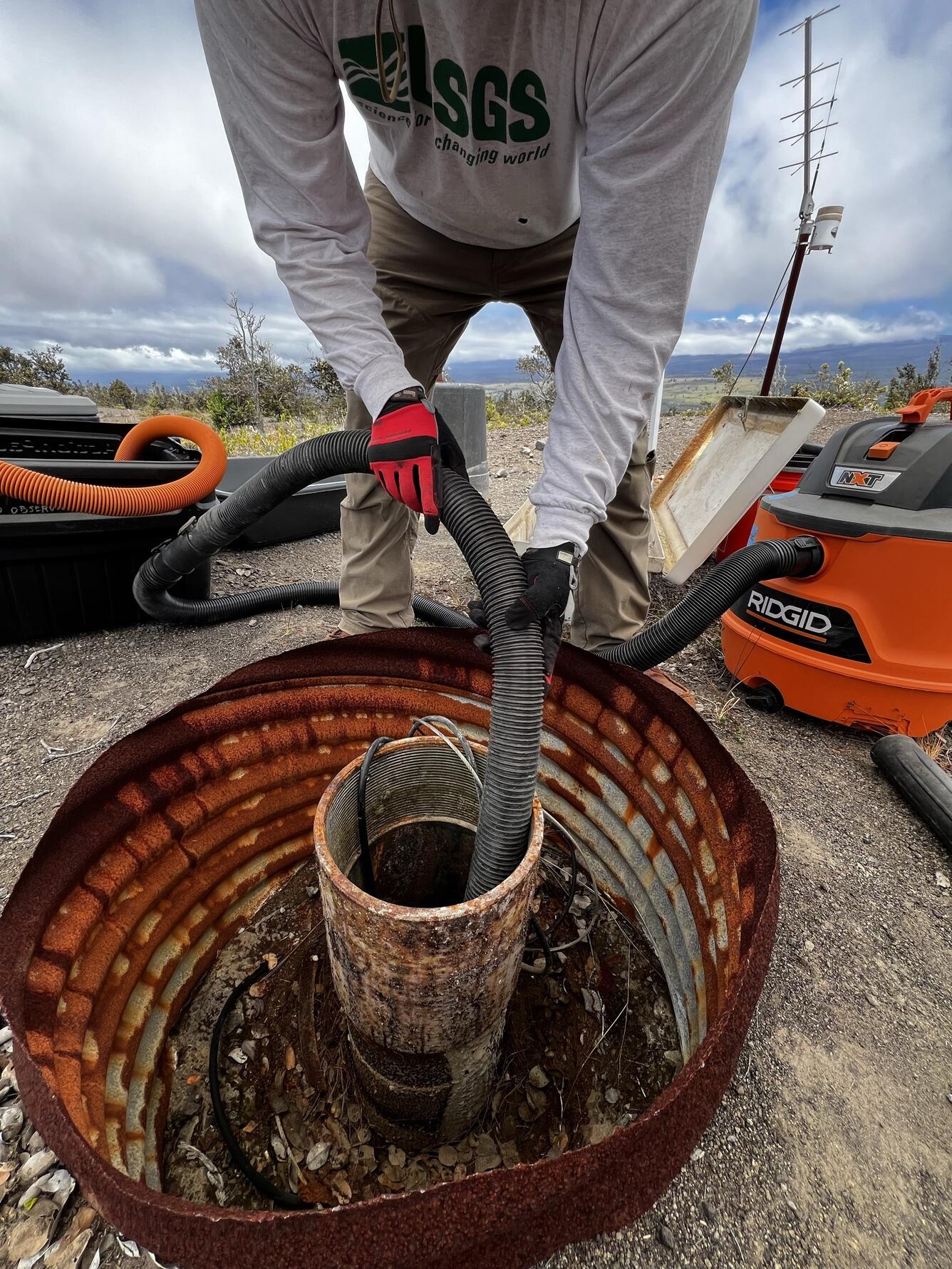 Color photograph of field engineer vacuuming sand from a borehole