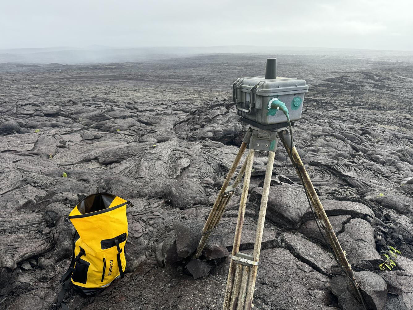 Color photograph of webcam on tripod located on an inactive lava flow field