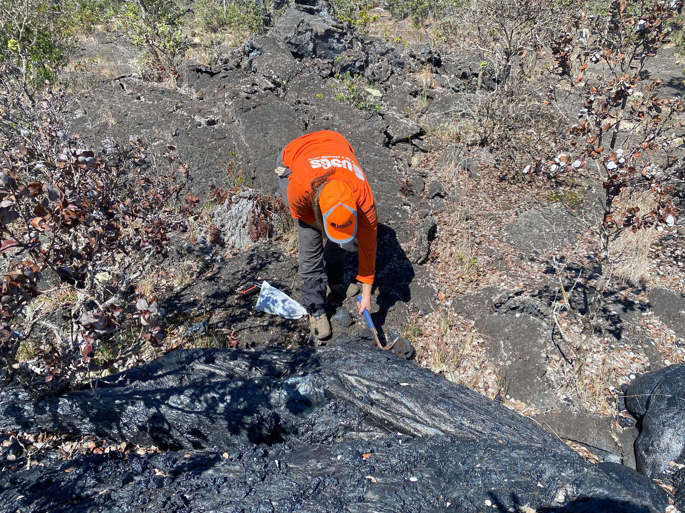 Color photograph of scientist taking a cold lava sample