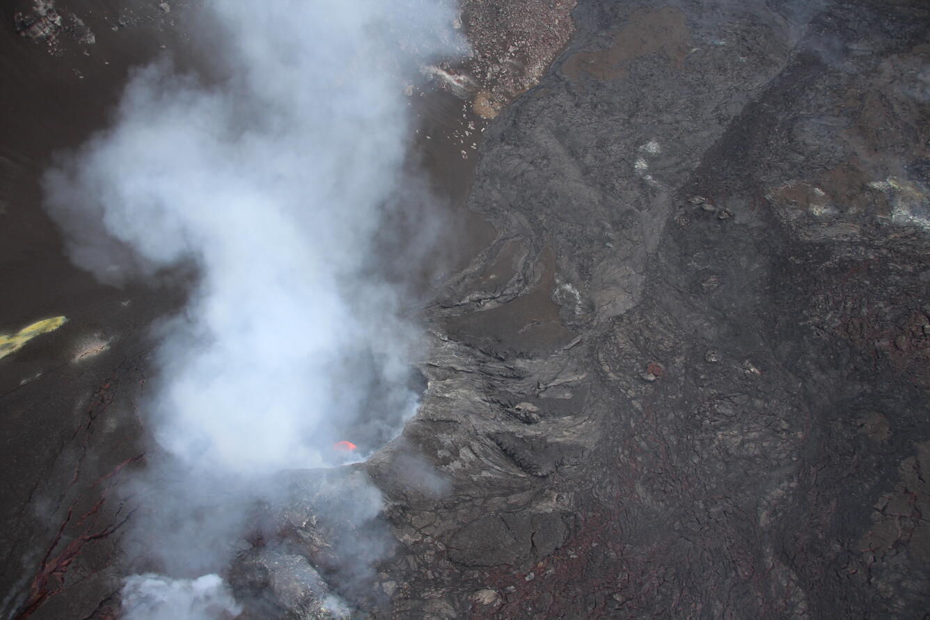 Color photograph of volcanic vent degassing and with a minor amount of incandescent lava visible within