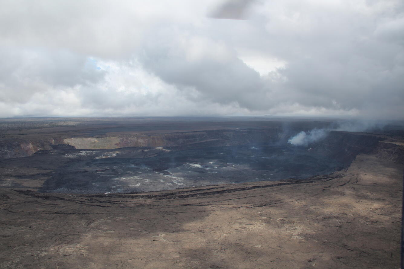 Color photograph of a caldera with an actively degassing vent near one wall