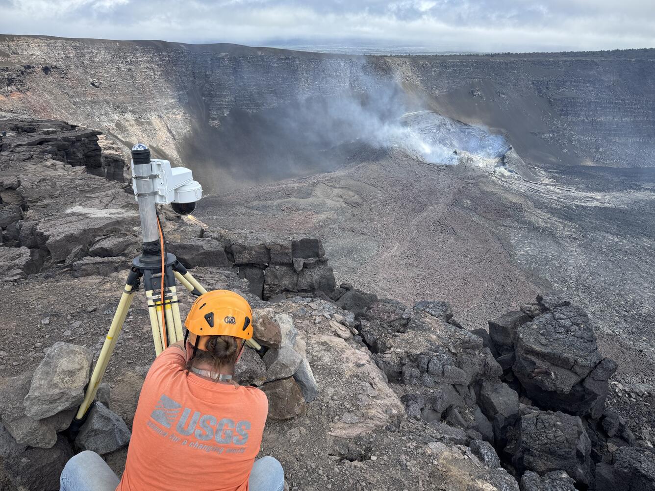 Color photograph of scientist adjusting camera near crater edge