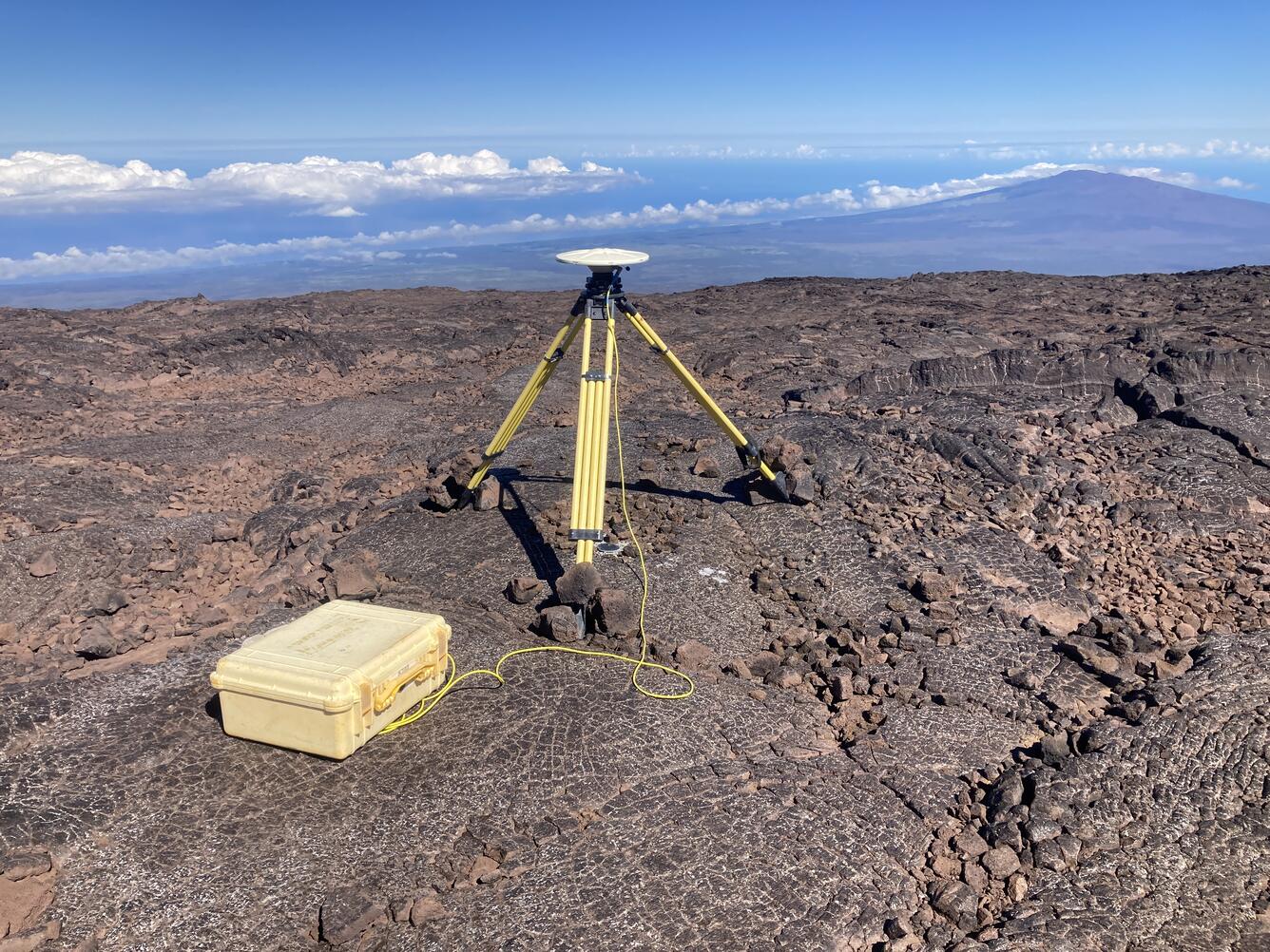 Color photograph of tripod on lava flow with mountain in the background