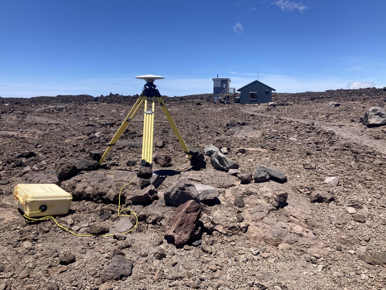 Color photograph of volcano monitoring station with cabin in background