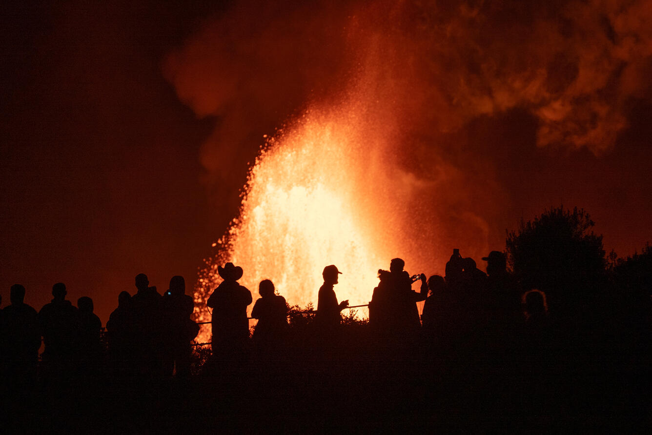 Color photograph of people watching an eruption at night