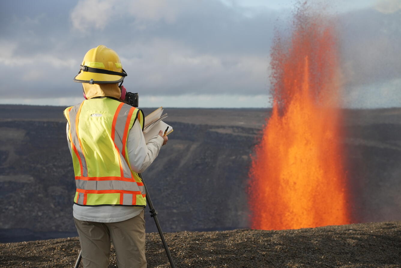 Color photograph of scientist observing lava fountain