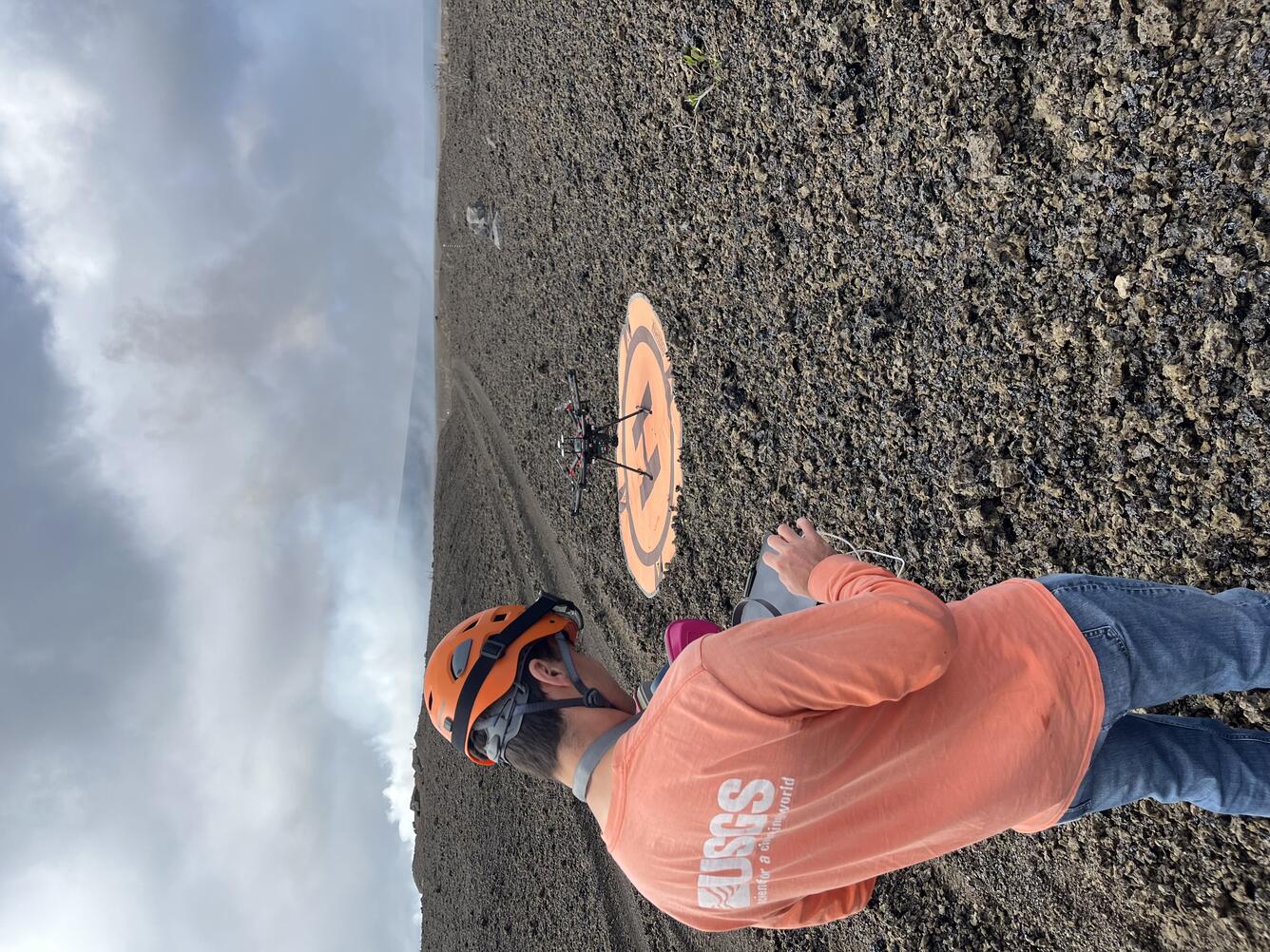 Color photograph of scientist operating UAS on volcanic terrain
