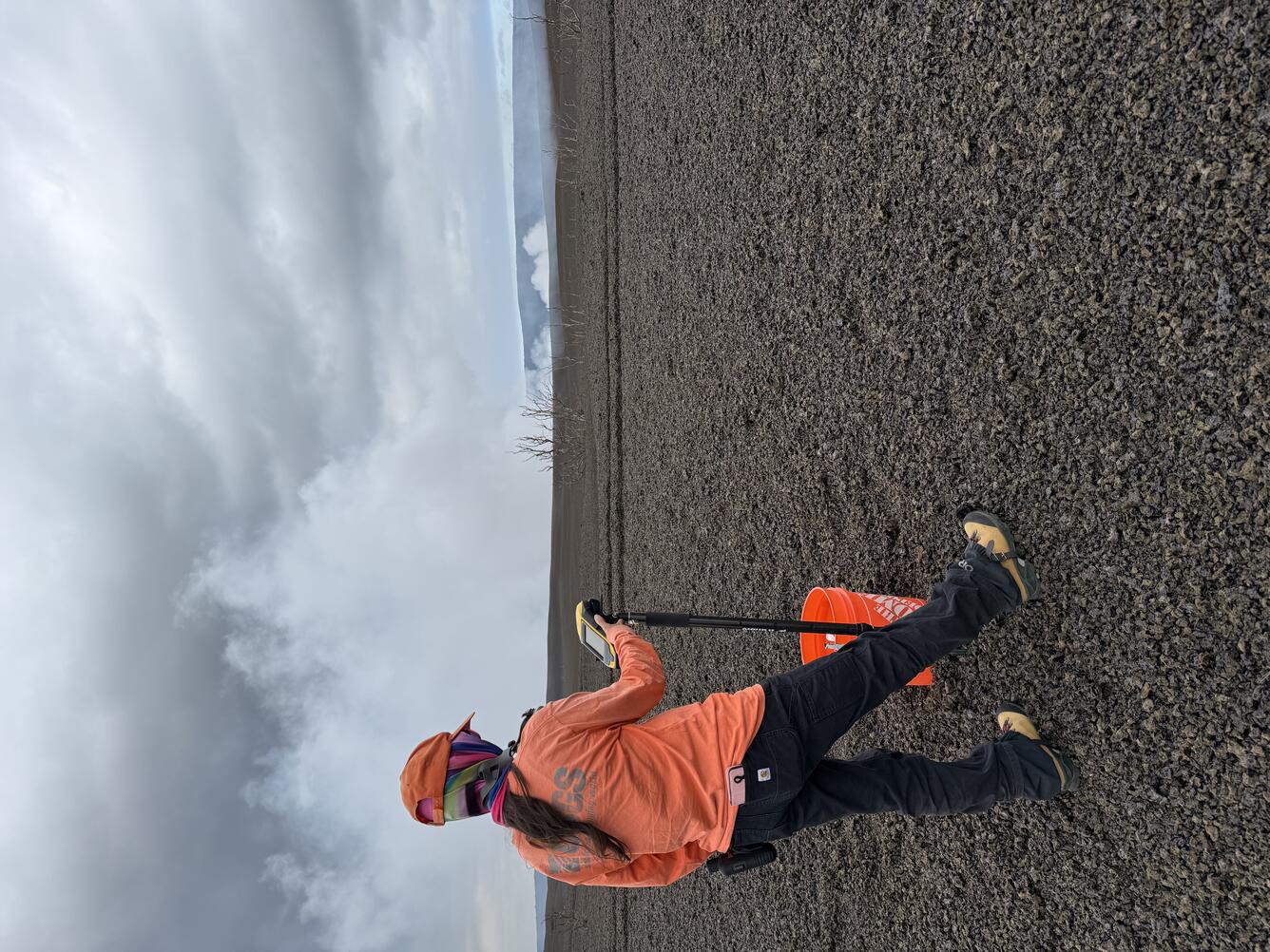 Color photograph of scientist taking measurement on volcanic landscape