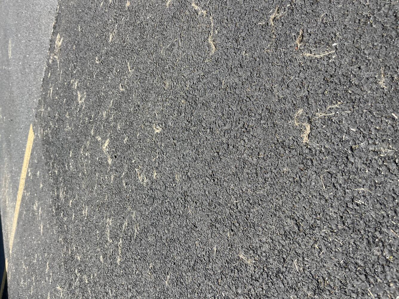 Color photograph of fine particles of volcanic glass on a paved road