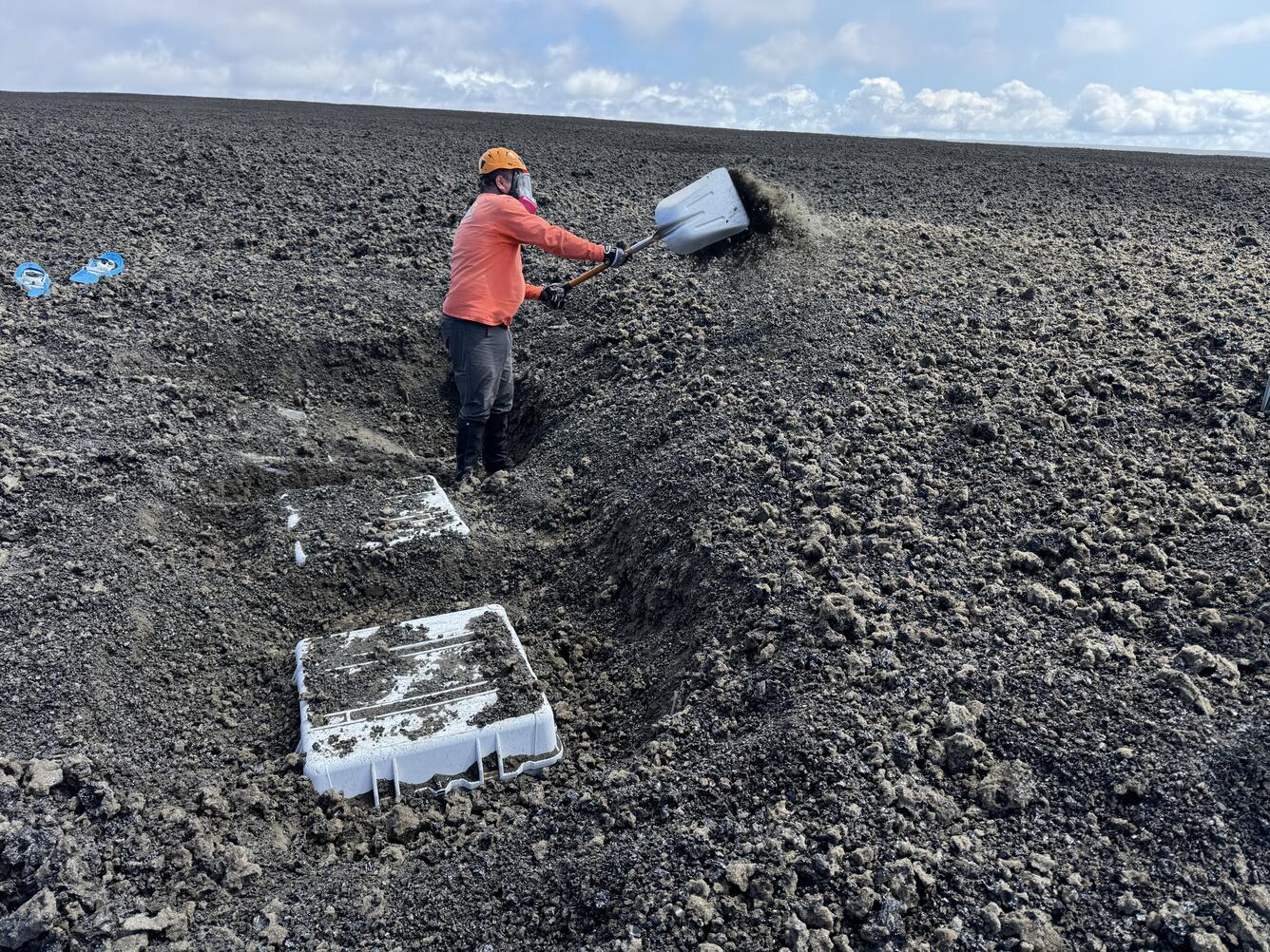 Color photograph of person digging a box out of the ground