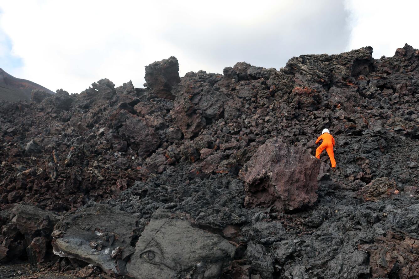 Color photograph of scientist on lava flow