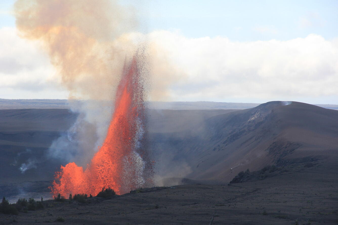 Color photograph of lava fountaining with crater rim in foreground