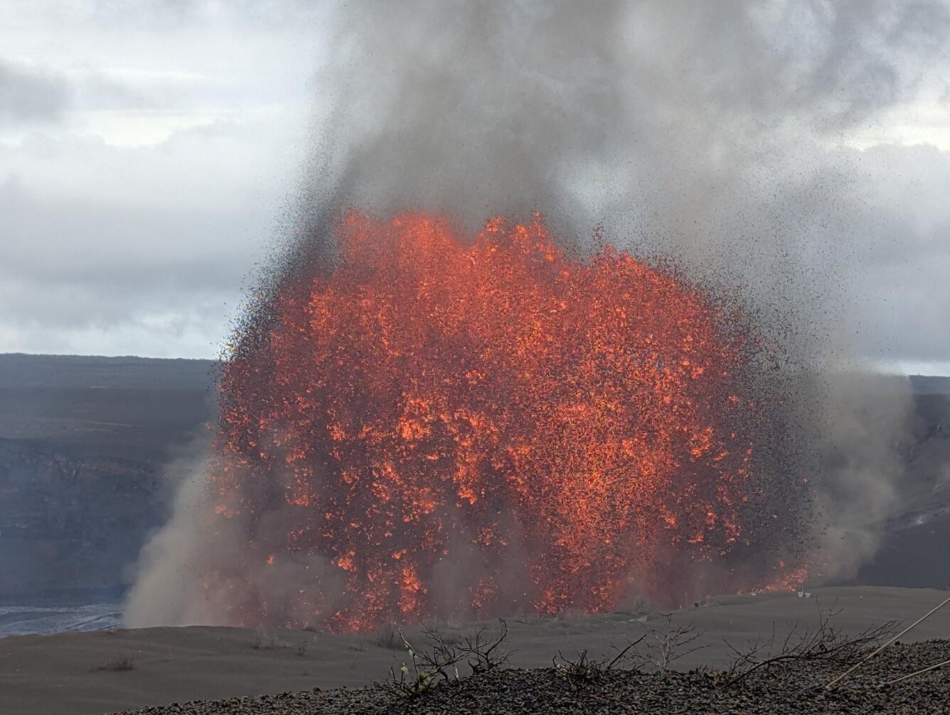 Color photograph of lava fountain with overcast skies in the background