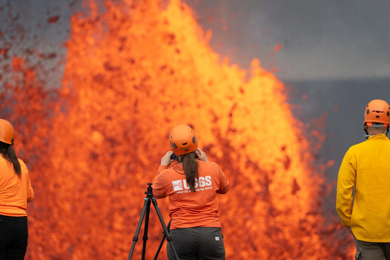 Color photograph of lava fountain with scientists in the foreground