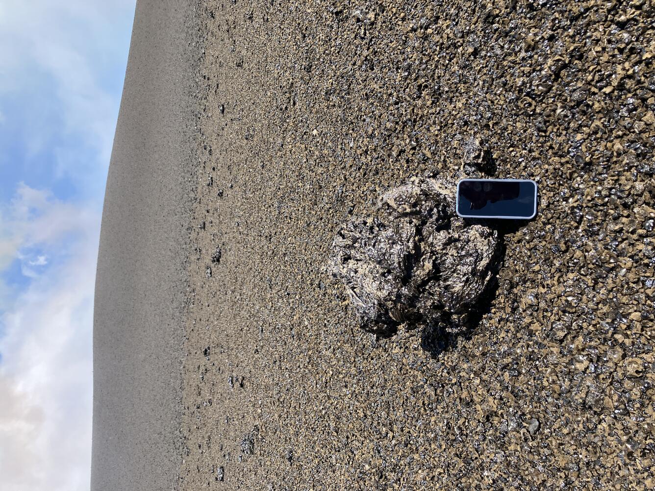 Color photograph of volcanic rock with smart phone next to it