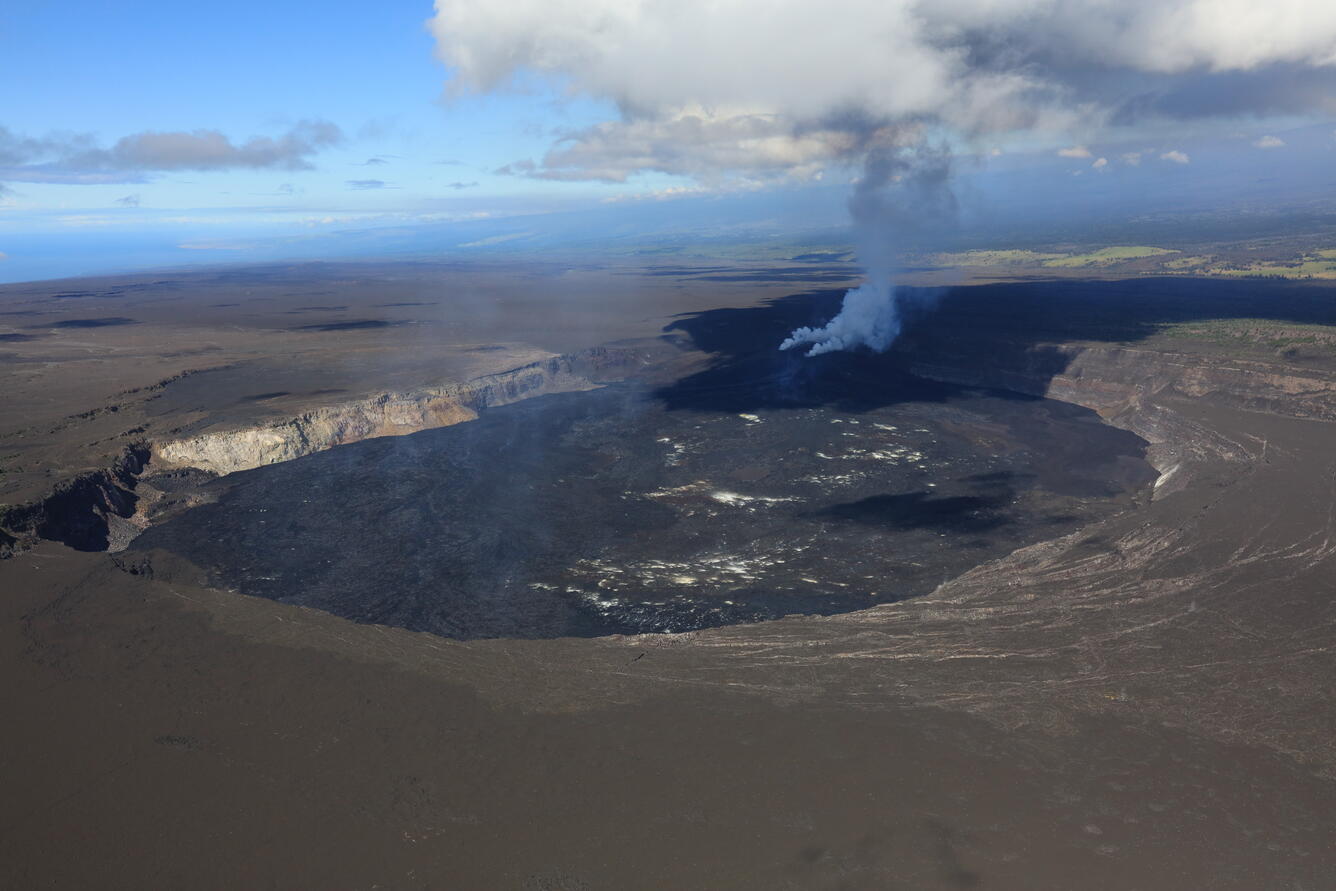 Color photograph of crater at summit of volcano with degassing plume from active vents