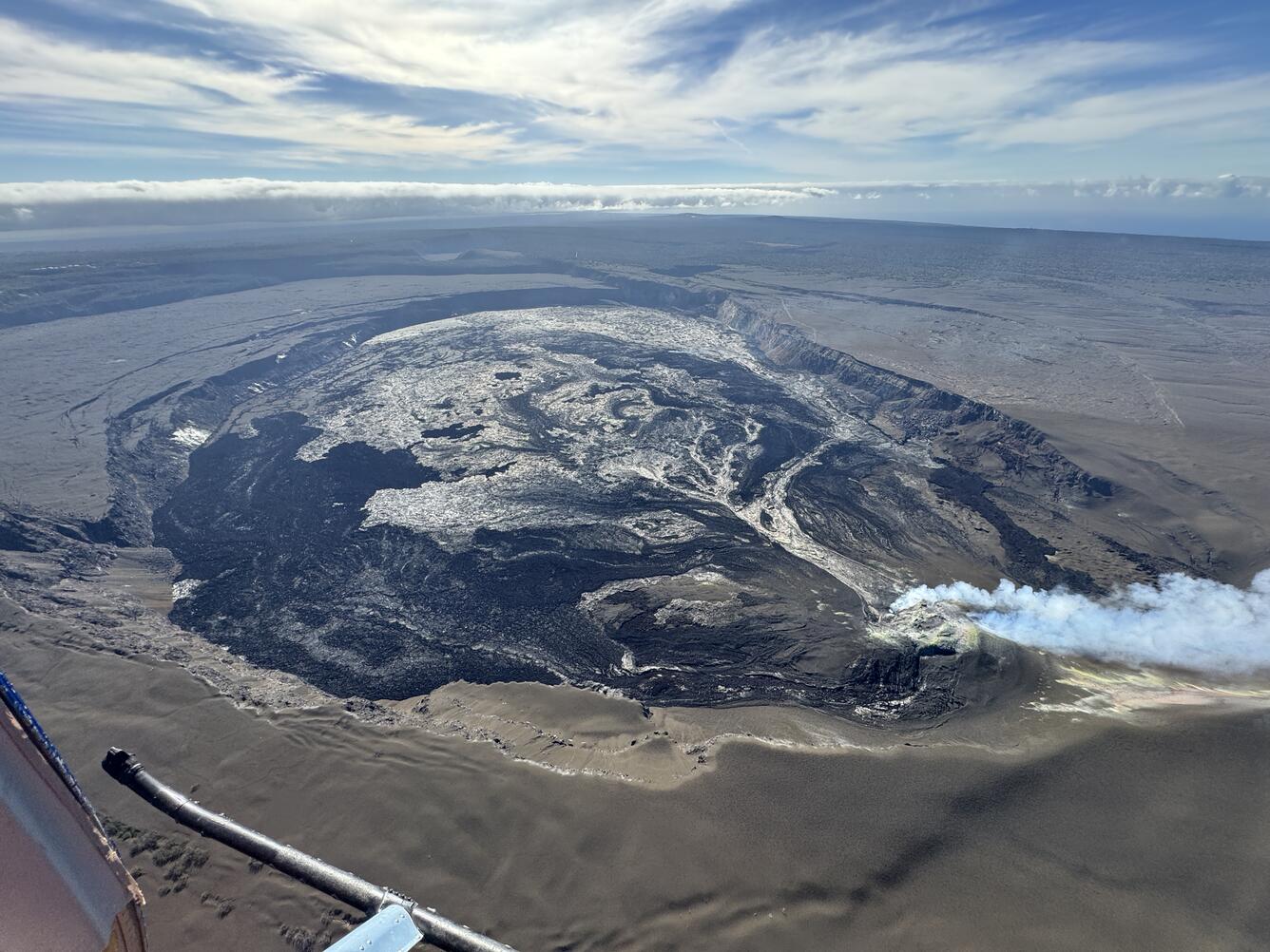 Color photograph of caldera at summit of volcano with gas plume from eruptive vents